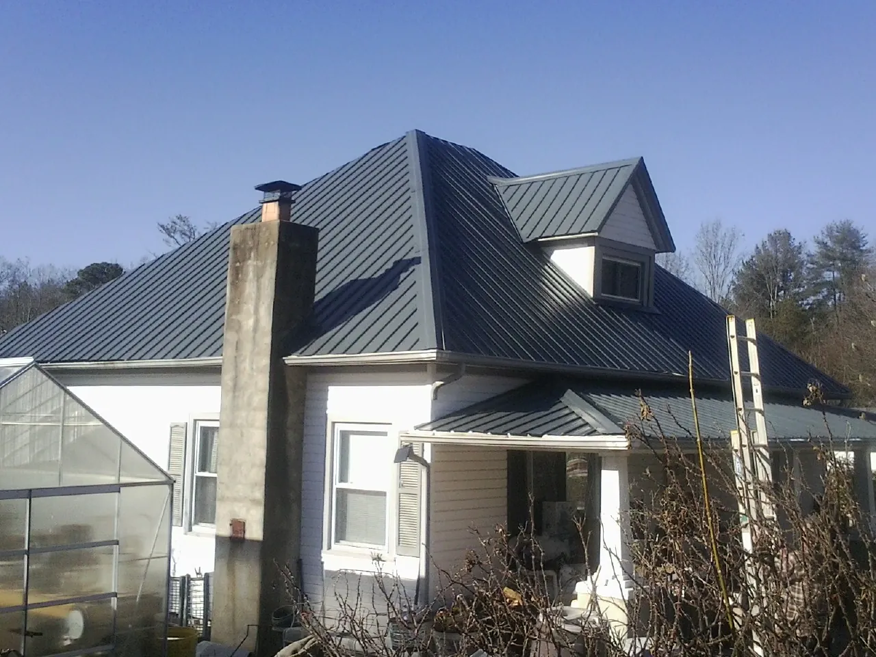 Dark blue standing seam metal roof on a white farmhouse with dormer — Slate & Tile Roof Repair by Roofing Brothers in Steptoe