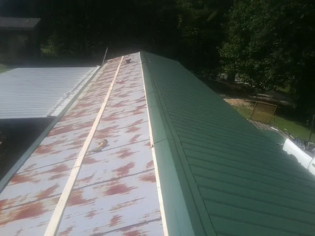Old rusted panels beside newly installed green metal roofing — Wind Damage Roof Repair by Roofing Brothers in Steptoe