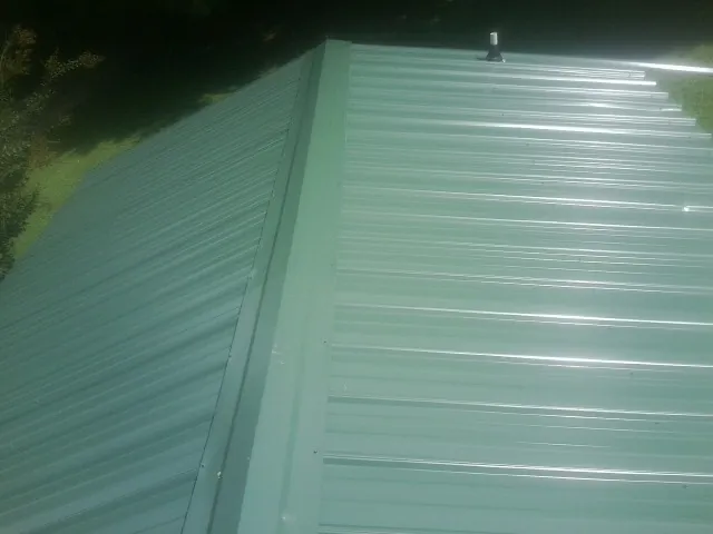 New green metal panels meeting at the ridge of a roof — Flat Roof Repair work by our crew in Steptoe