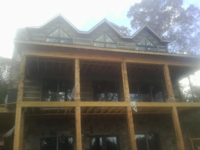 Dormers and porch framing on a large log home under construction — Roof Coating work by our crew in Steptoe