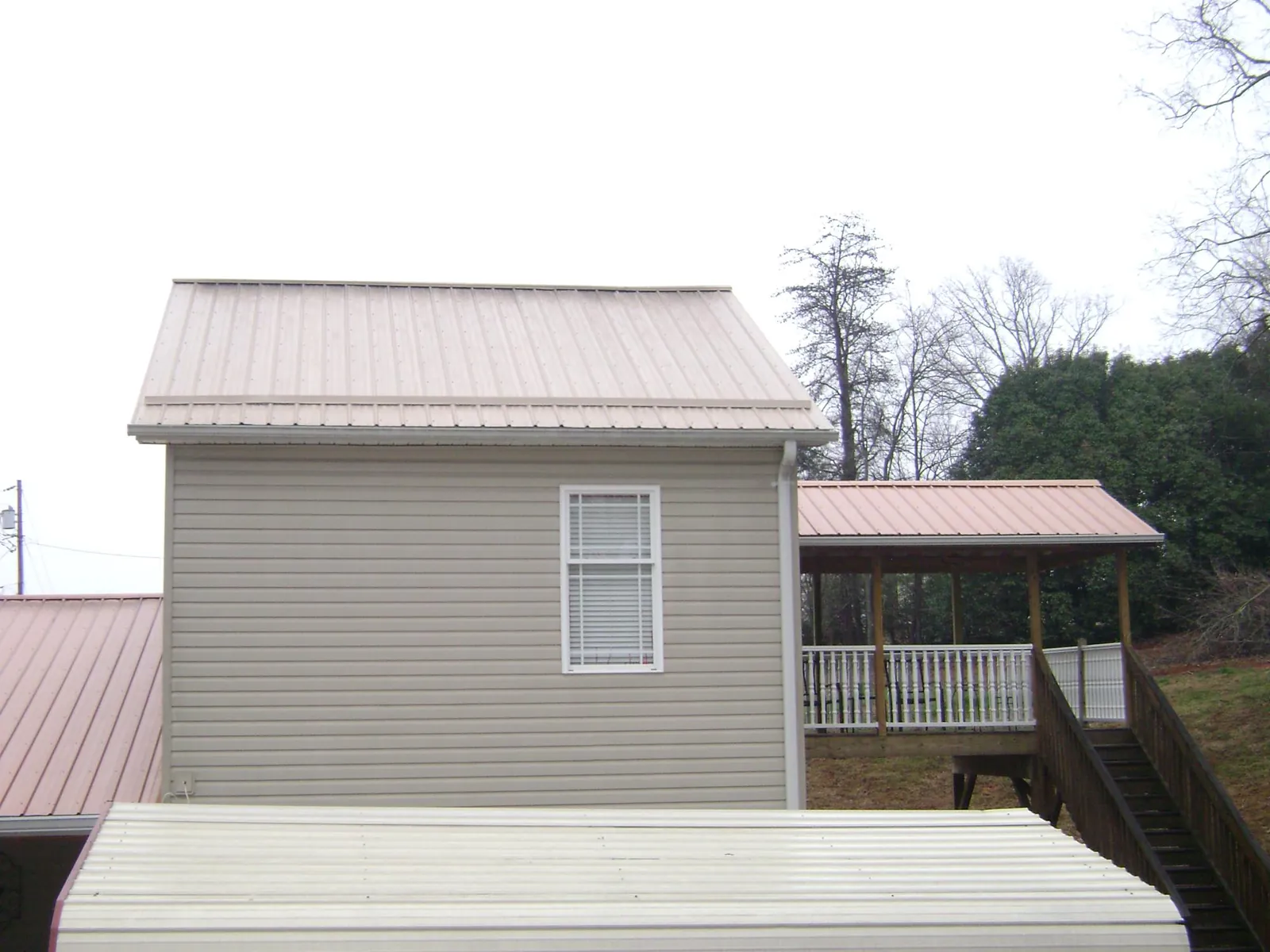 Tan metal roofs on a two story addition and attached porch, from a Roof Replacement job in Steptoe