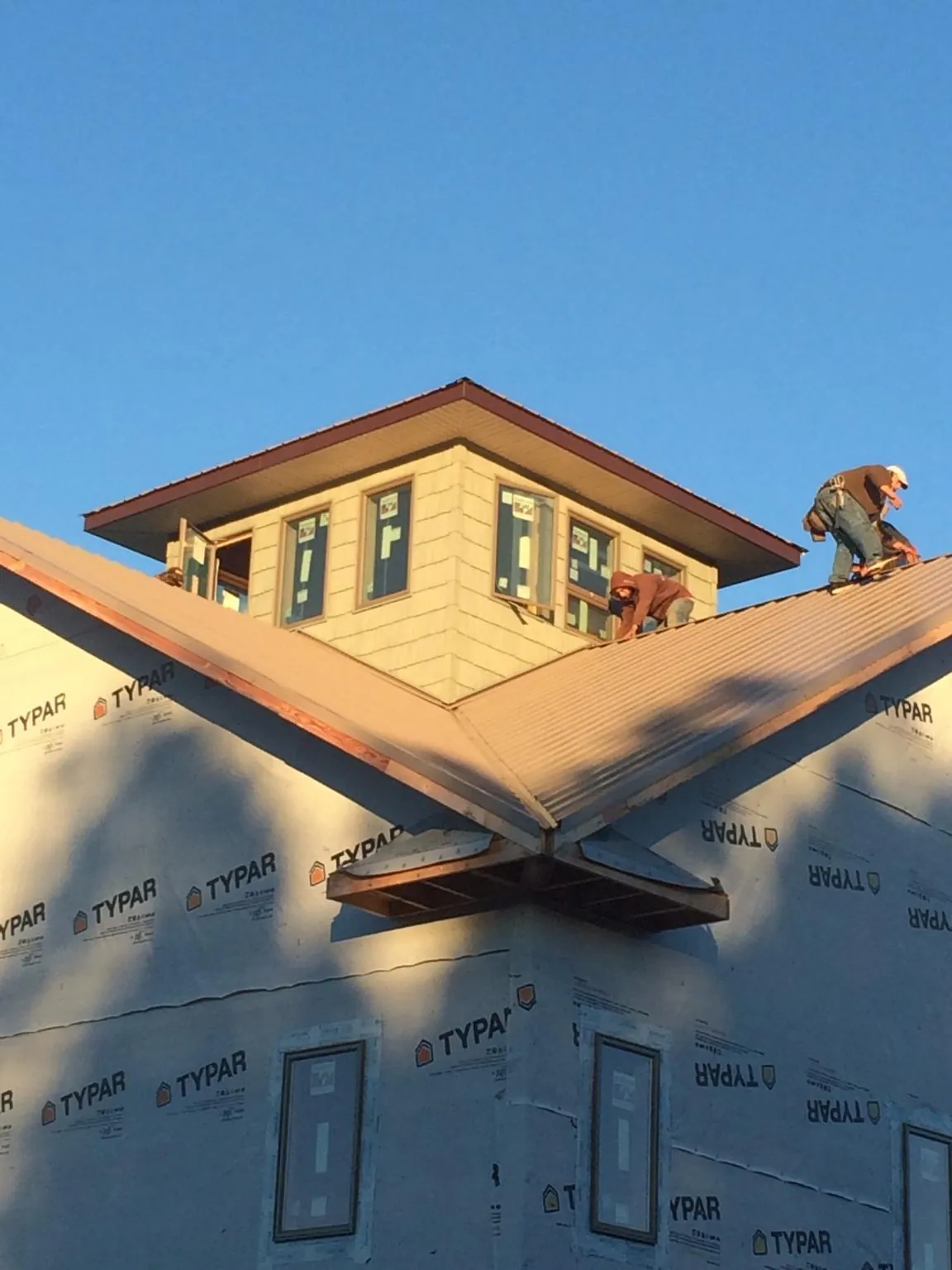 Roofers working around a rooftop cupola on a new metal roof at sunset — Roof Waterproofing in Steptoe by Roofing Brothers